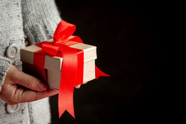 woman-s-hand-holding-gift-box-with-red-ribbon